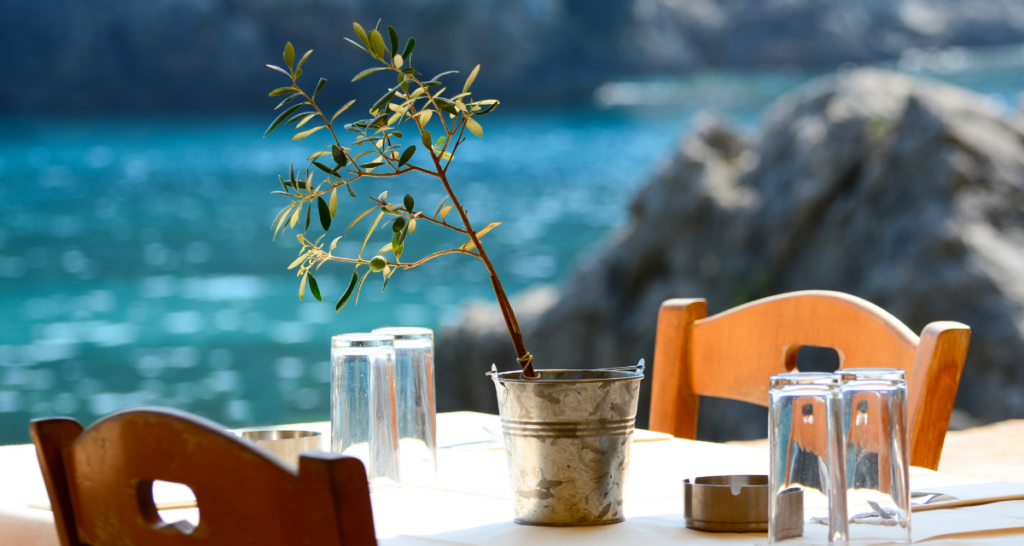 a table of two with wooden chairs of a greek tavern with a sea view